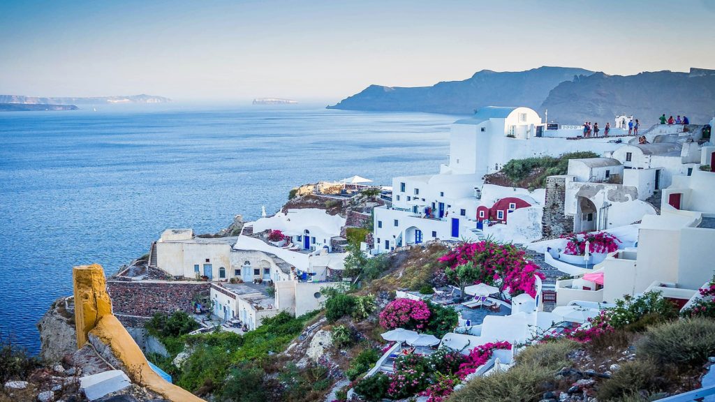 Griechenlands Küste mit seinen weißen gebäuden und violetten Blumenfarben ist traumhaft